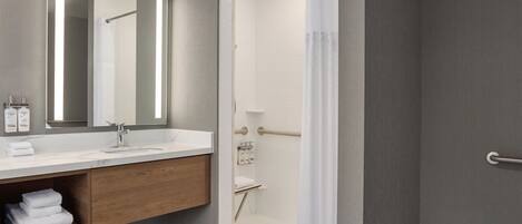 Un baño moderno con un espejo grande, un lavamanos y una zona de ducha.