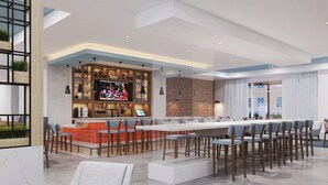 Een moderne barruimte met een lange bar, verschillende barkrukken en een televisiescherm.