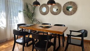 Ein Essbereich mit einem Holztisch, schwarzen Stühlen und Pendelleuchten.