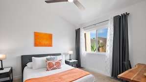 Une chambre d’hôtel moderne dotée d’un grand lit, d’une table à manger, d’un ventilateur de plafond et d’une fenêtre avec des rideaux.
