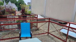 An outdoor seating area with a table and two chairs, surrounded by a red metal fence. - Large Studio in quiet inner-city location (Dinan)