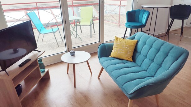 A living room with a sofa, a TV, and a small table. - Large Studio in quiet inner-city location (Dinan)