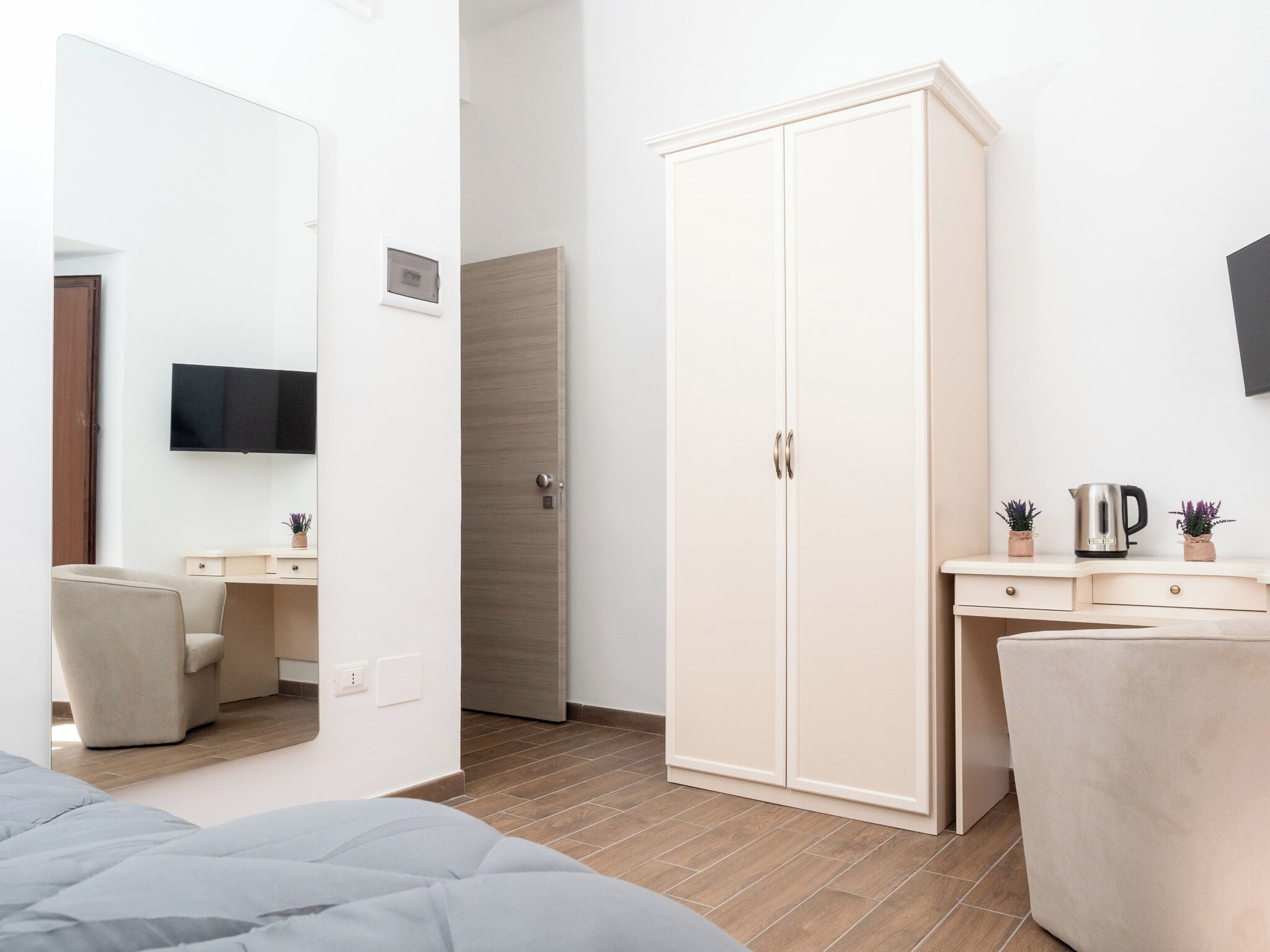 Ein modernes Schlafzimmer mit einem Bett, einem Kleiderschrank, einem Schreibtisch und einem an der Wand befestigten Fernseher.