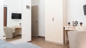 Un dormitorio moderno con cama, armario, escritorio y televisor montado en la pared.