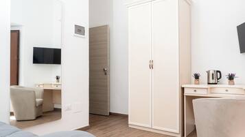 Ein modernes Schlafzimmer mit einem Bett, einem Kleiderschrank, einem Schreibtisch und einem an der Wand befestigten Fernseher.
