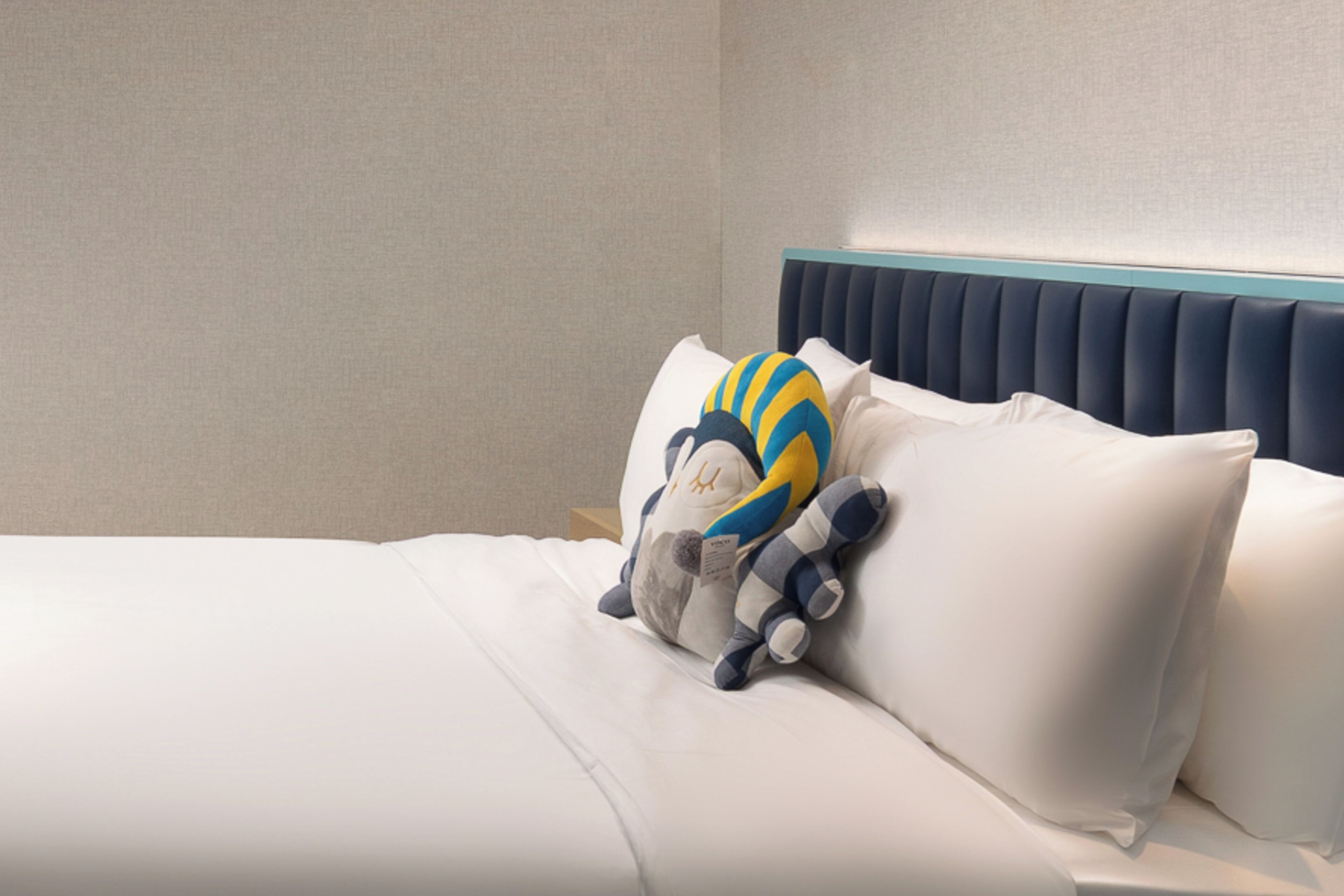 A bed with white bedding and a plush toy.