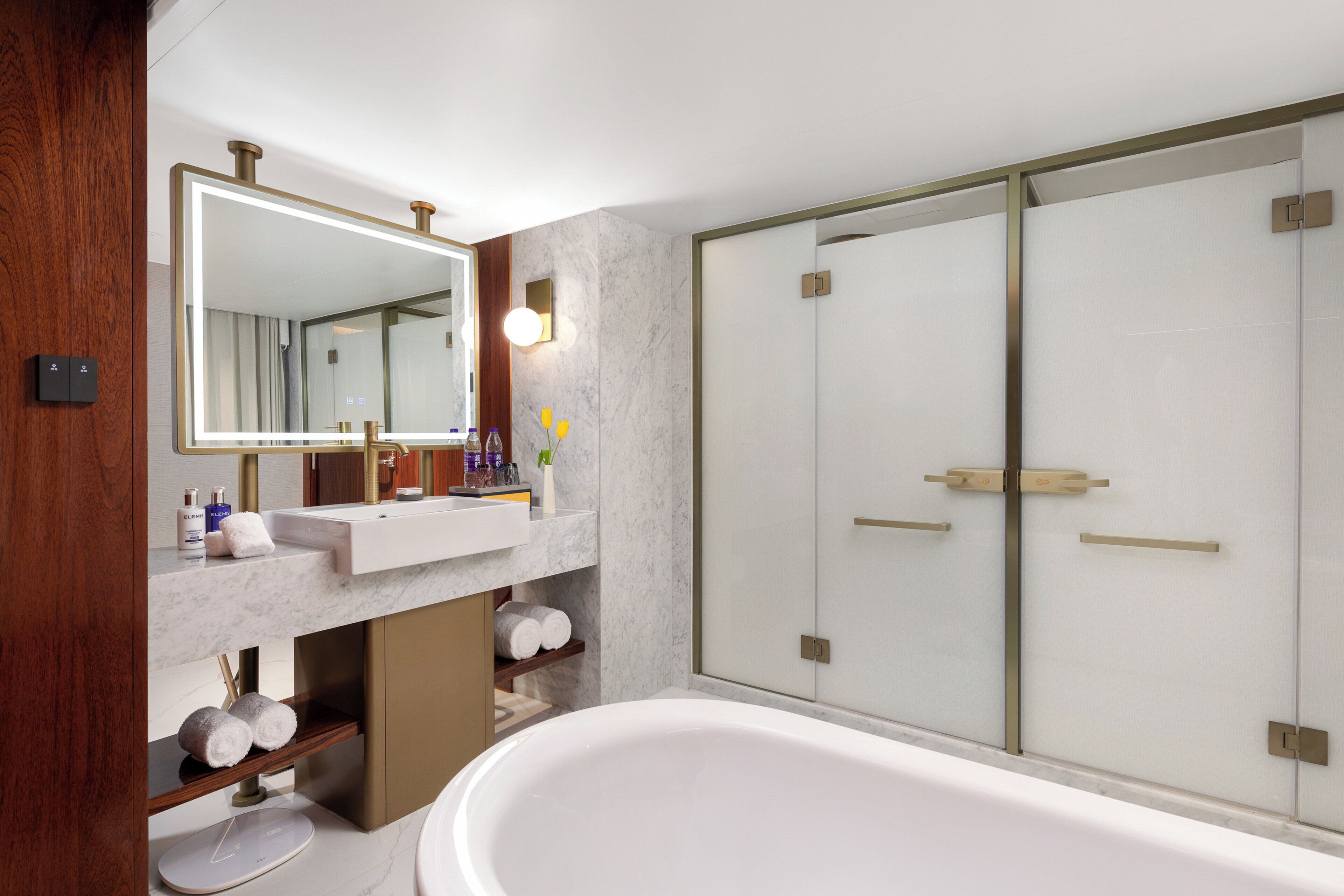 A modern bathroom with a large mirror, a bathtub, a vanity with a sink, and a shower area.