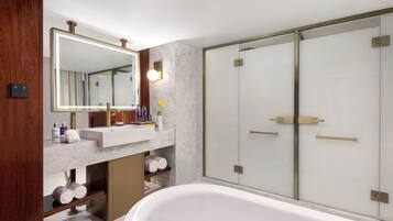 A modern bathroom with a large mirror, a bathtub, a vanity with a sink, and a shower area.