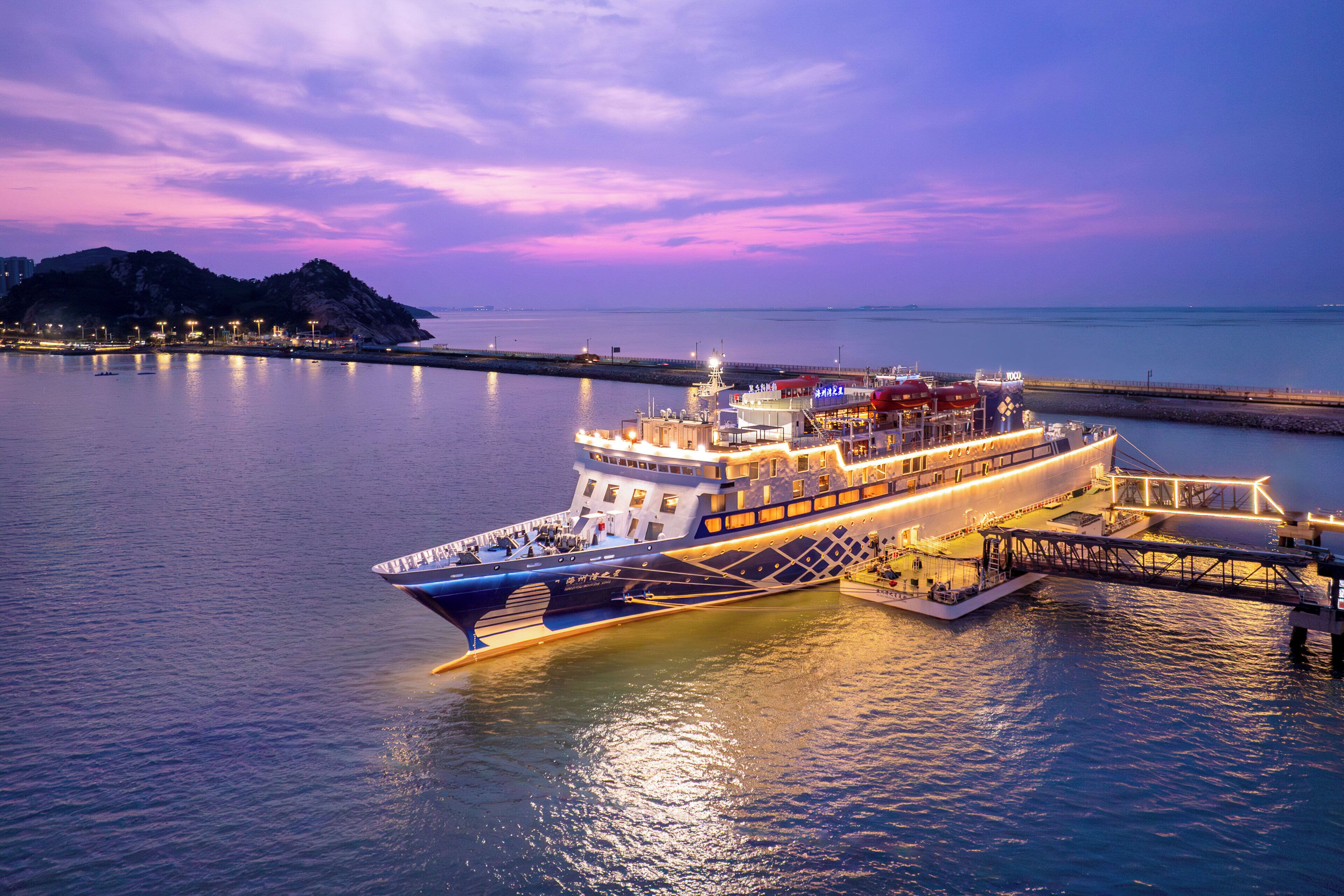 A large, illuminated ferry docked at a pier during twilight.