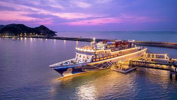 A large, illuminated ferry docked at a pier during twilight.