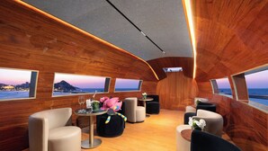 Un interior lujoso con paneles de madera, asientos confortables y amplios ventanales que ofrecen vistas al océano.