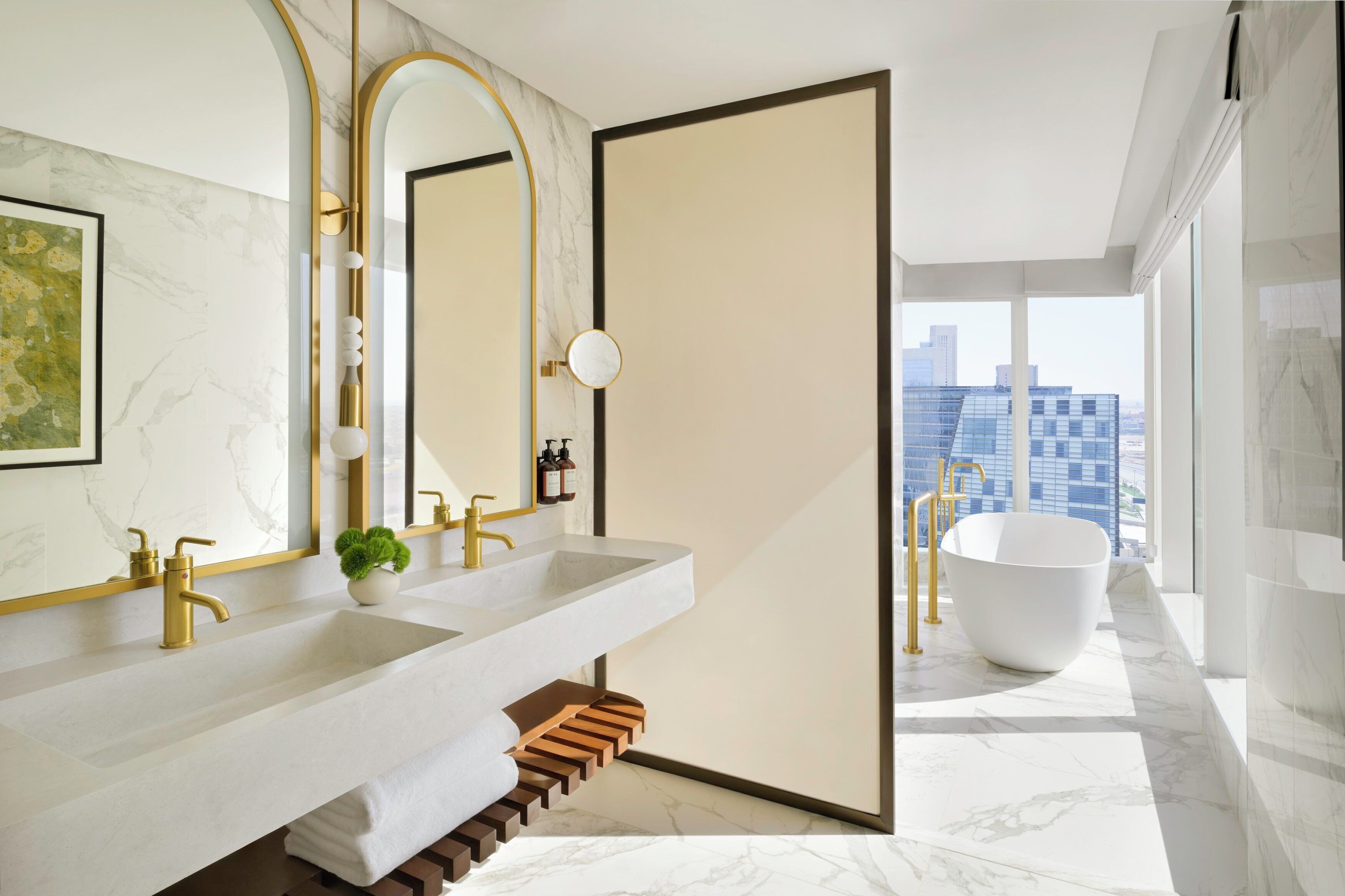 A modern bathroom with dual sinks, a large mirror, and a freestanding bathtub.
