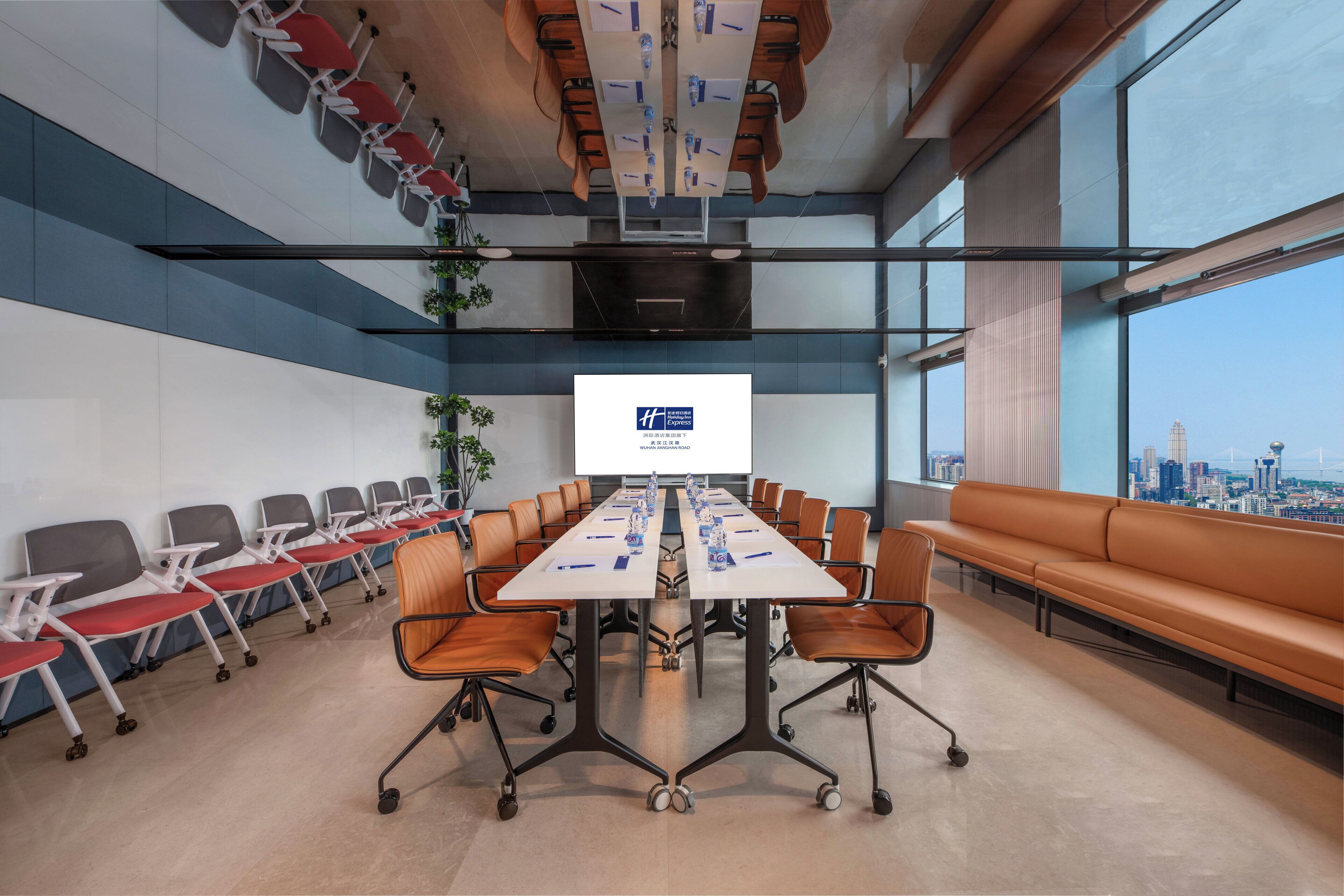 Une salle de conférence avec une longue table, des chaises, un grand écran et une vue sur la ville.