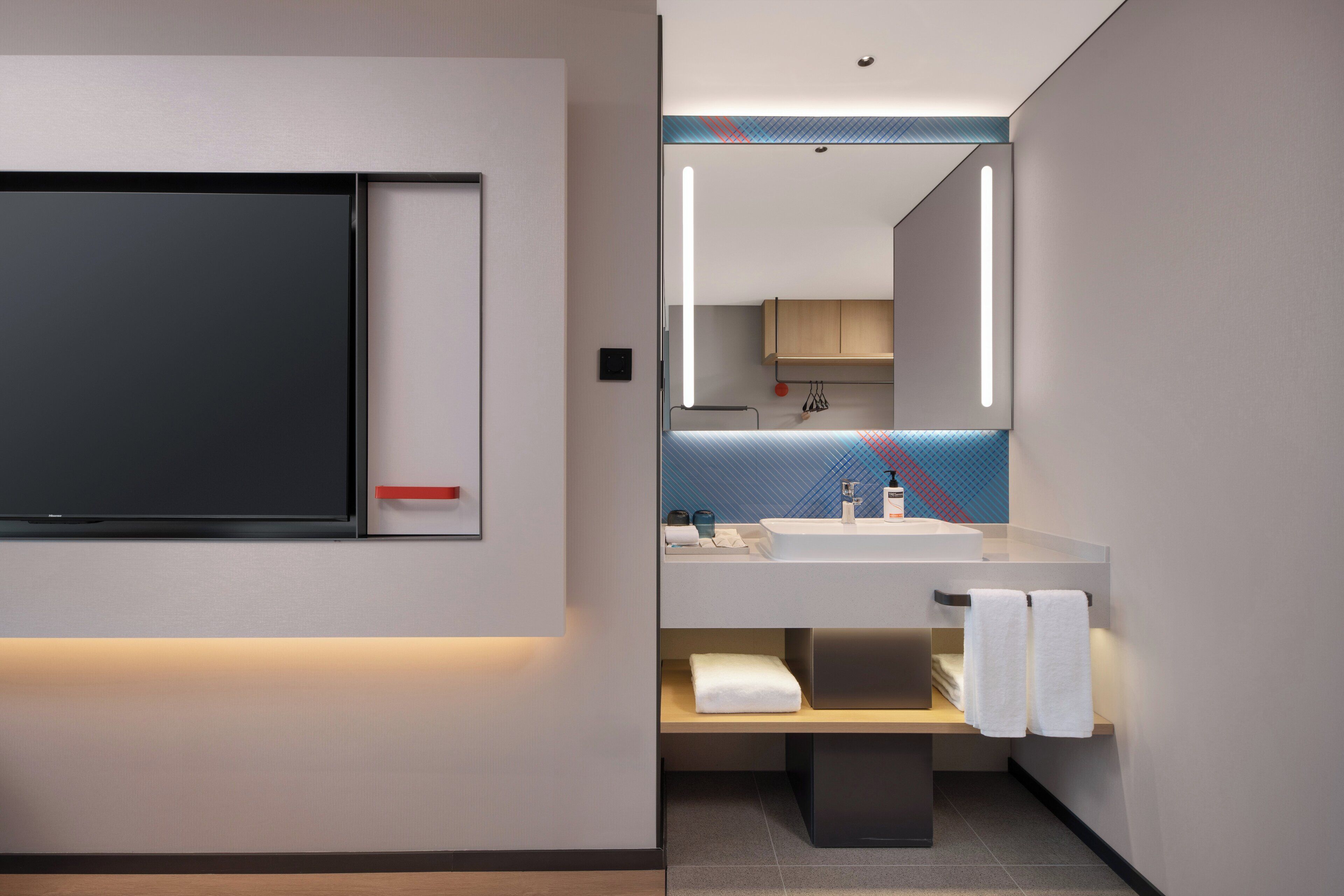 A modern bathroom with a large mirror, a sink, and a towel rack.