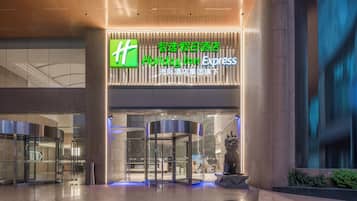 Entrada de um hotel Holiday Inn Express, com uma porta giratória e uma grande placa iluminada.