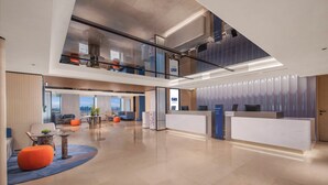 Un'ampia hall con reception, aree lounge e vista sullo skyline cittadino.