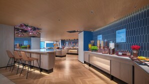 Una hall moderna di un hotel, con pavimento in legno, una reception e un bancone con diversi servizi.