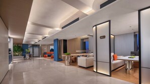 Una hall d'albergo moderna con ampi spazi, una zona salotto centrale e una reception ben visibile.