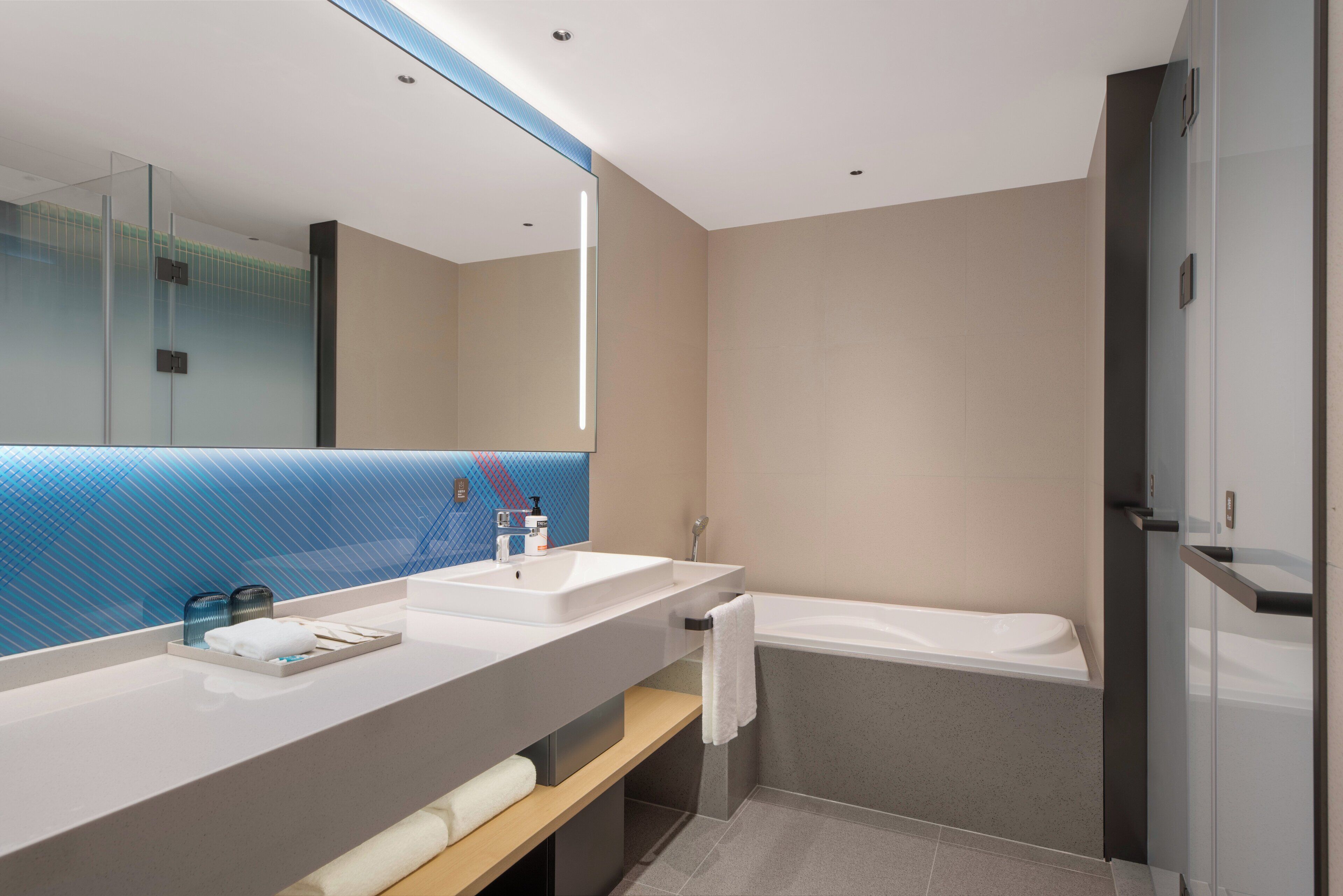Une salle de bain moderne avec deux vasques, un grand miroir, une baignoire et une cabine de douche en verre.