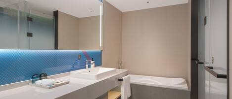 Une salle de bain moderne avec deux vasques, un grand miroir, une baignoire et une cabine de douche en verre.
