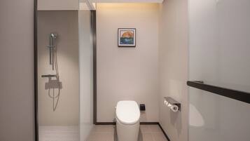 Un baño moderno con cabina de ducha de vidrio, inodoro y un cuadro enmarcado en la pared.