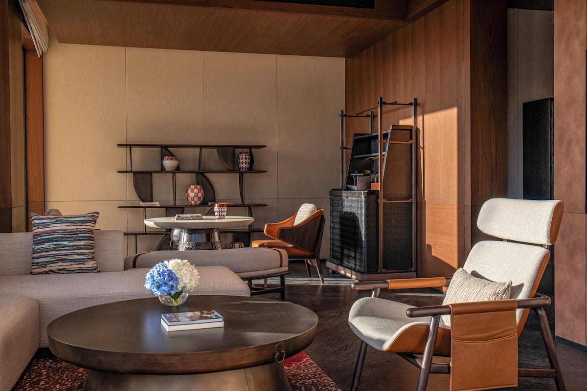 A modern living room with a sofa, armchair, coffee table, and fireplace.