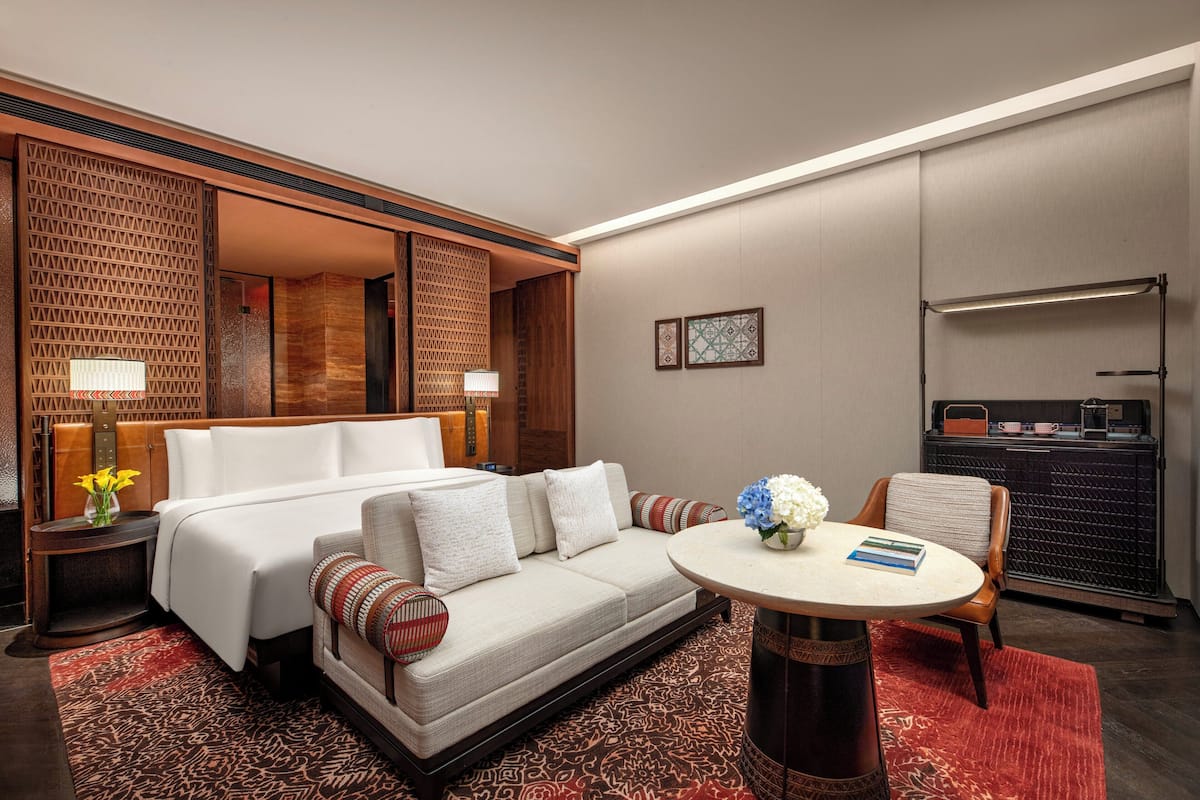 Habitación de hotel con cama, sofá, mesa de comedor y una pequeña cocina.