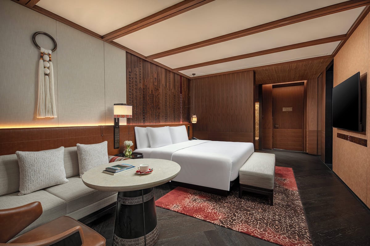 Una habitación de hotel con cama, sofá, mesa de centro y televisión.
