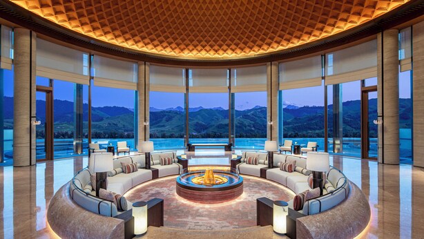 A luxurious lobby with a circular seating area, large windows offering mountain views, and a wooden ceiling. - Hotel Indigo Nalati by IHG (Xinyuan)