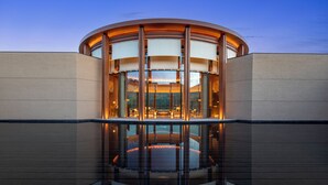 A modern building with a circular central area, large glass windows, and a reflective floor. - Hotel Indigo Nalati by IHG (Xinyuan)