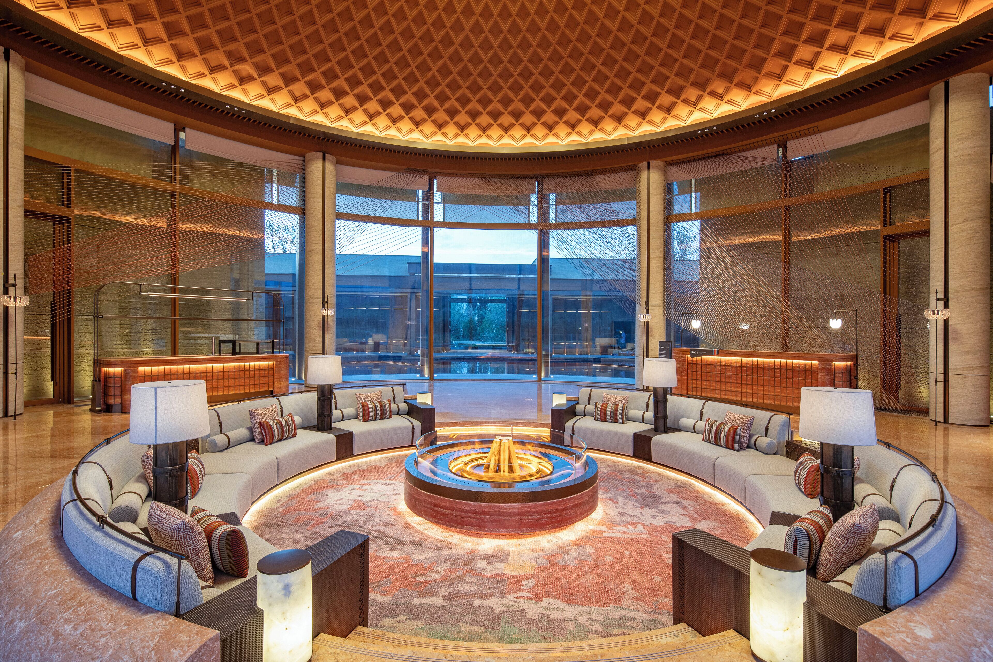 A spacious lobby with a circular seating area, large windows, and a modern ceiling design.