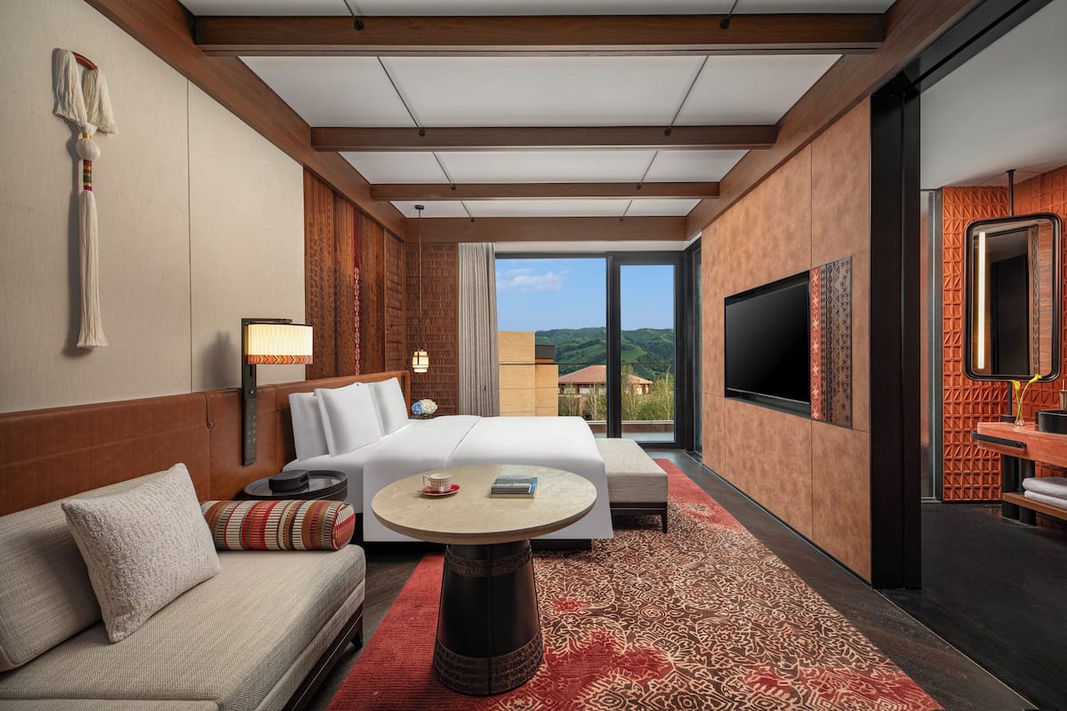 Una habitación de hotel con cama, sofá, mesa redonda y televisión.