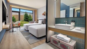 A modern hotel room with a large bed, a desk, a chair, and a bathroom with a large mirror and sink. - Holiday Inn Express Nalati by IHG (Xinyuan)