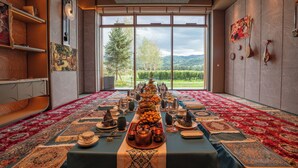 A dining area with a long table set for a meal, large windows, and a view of the outdoors. - Holiday Inn Express Nalati by IHG (Xinyuan)