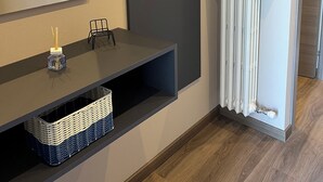 A modern bathroom with a dark vanity, a mirror, hooks on the wall, a blue vase, and a white towel rack. - Blue Apartment - Verona & Lake (San Vito Al Mantico)