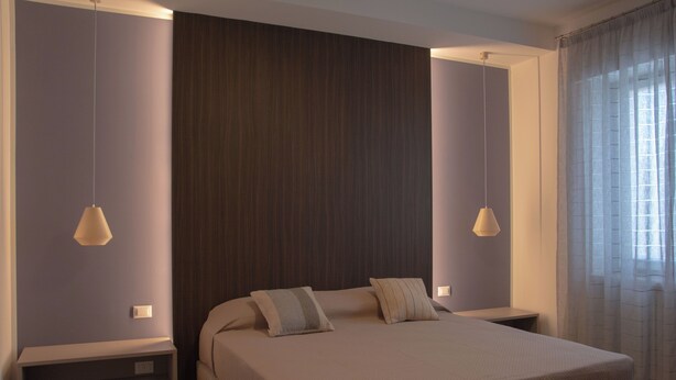 A modern bedroom with a large bed, two bedside tables, and a built-in bench. - Blue Apartment - Verona & Lake (San Vito Al Mantico)