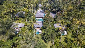 Un complexe hôtelier comprenant plusieurs villas, une piscine centrale et une végétation tropicale luxuriante.