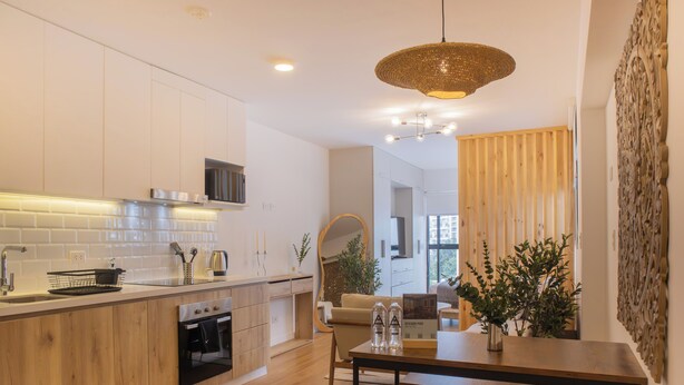 A modern kitchen with wooden cabinets, a built-in oven, and a dining area with a wooden table and bench. - Pendragon by Wynwood House (Lima)