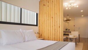 A modern bedroom with a large bed, a wooden accent wall, a small desk, and a chair. - Pendragon by Wynwood House (Lima)