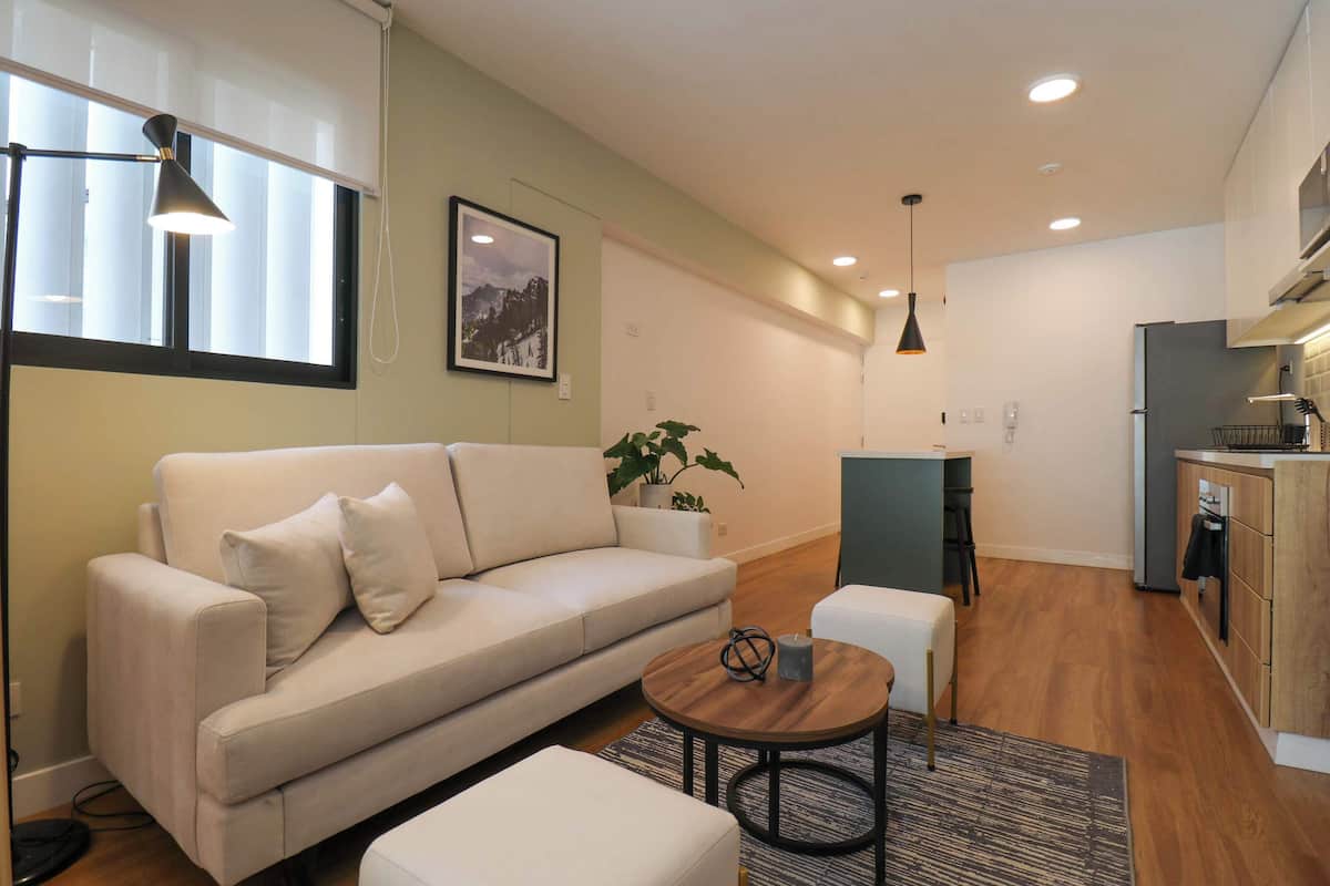 A modern living room with a sofa, a coffee table, and a kitchen area in the background.