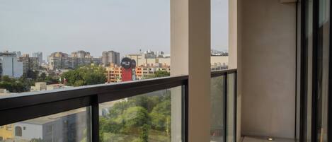 A balcony with a city view, glass railings, and a tiled floor.