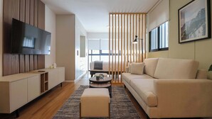 A modern living room with a flat-screen TV, a sofa, a coffee table, and a wooden partition. - Pendragon by Wynwood House (Lima)