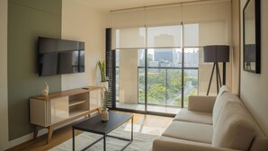 A modern living room with a flat-screen TV, a wooden entertainment unit, a white sofa, a coffee table, and a floor lamp. - Pendragon by Wynwood House (Lima)