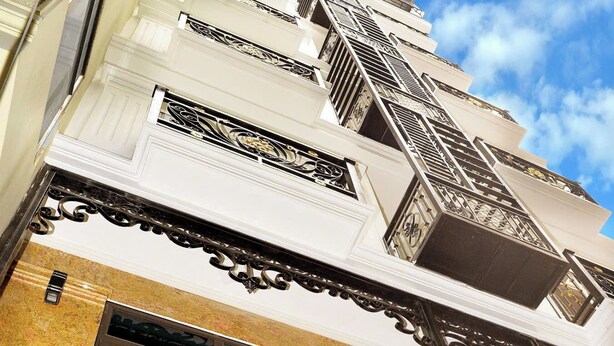 Un edifici de diverses plantes amb una escalinata destacada i baranes metàl·liques ornamentals.