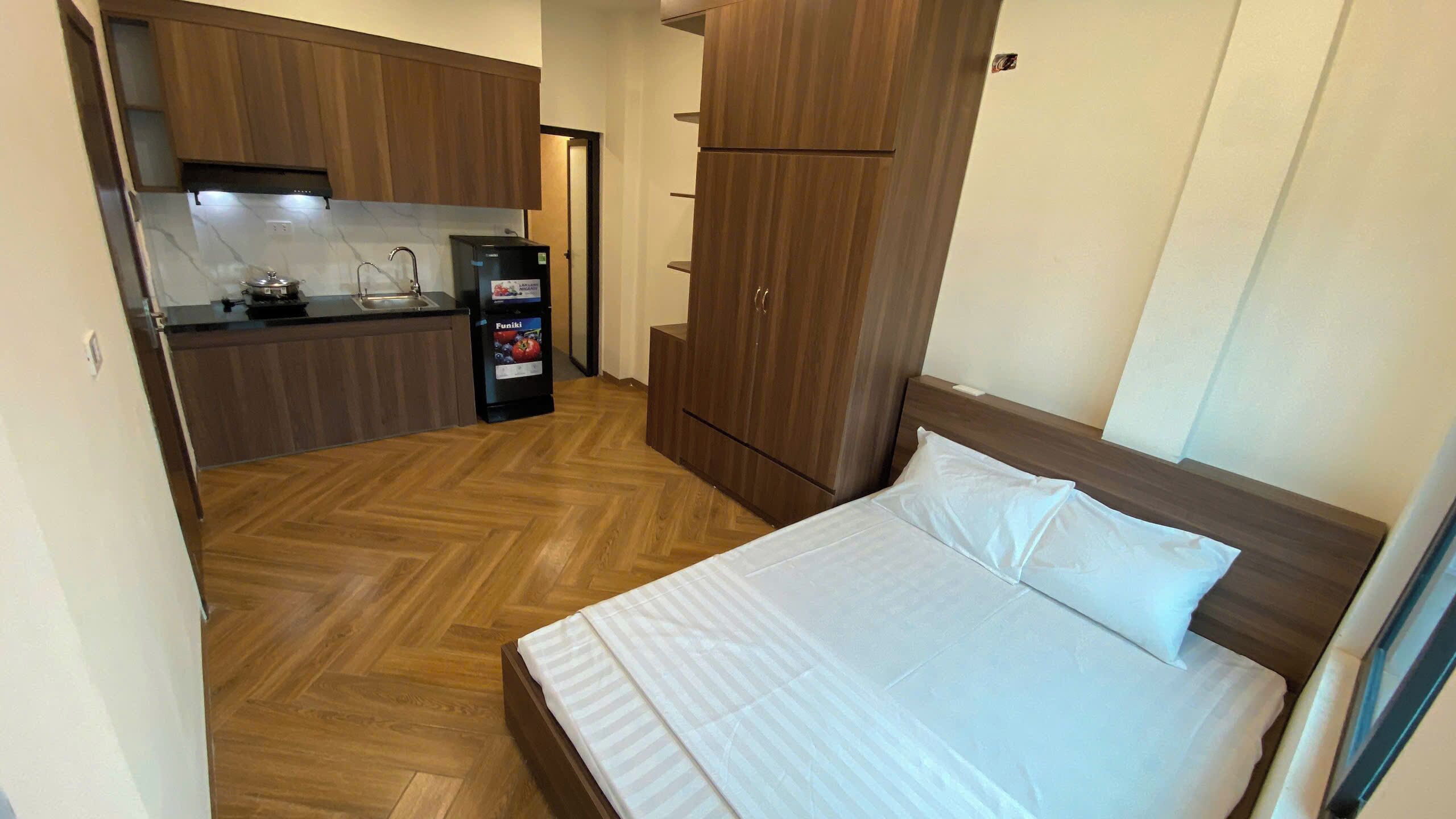 Ein kleines Zimmer mit Bett, Küchenzeile und Kleiderschrank.