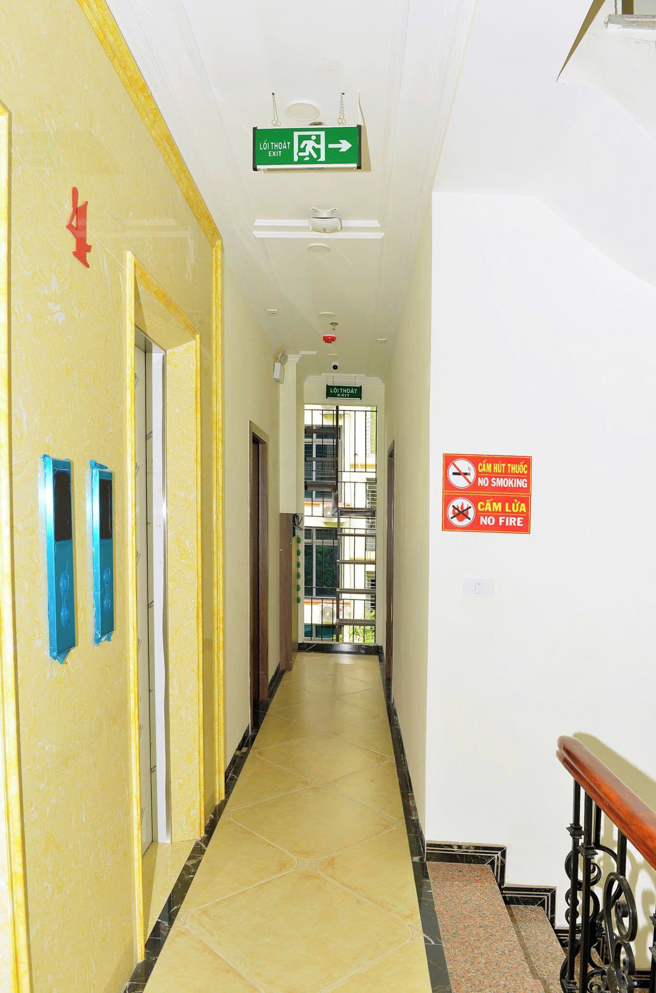 A hallway with yellow walls, a green exit sign, and a no smoking/fire sign.