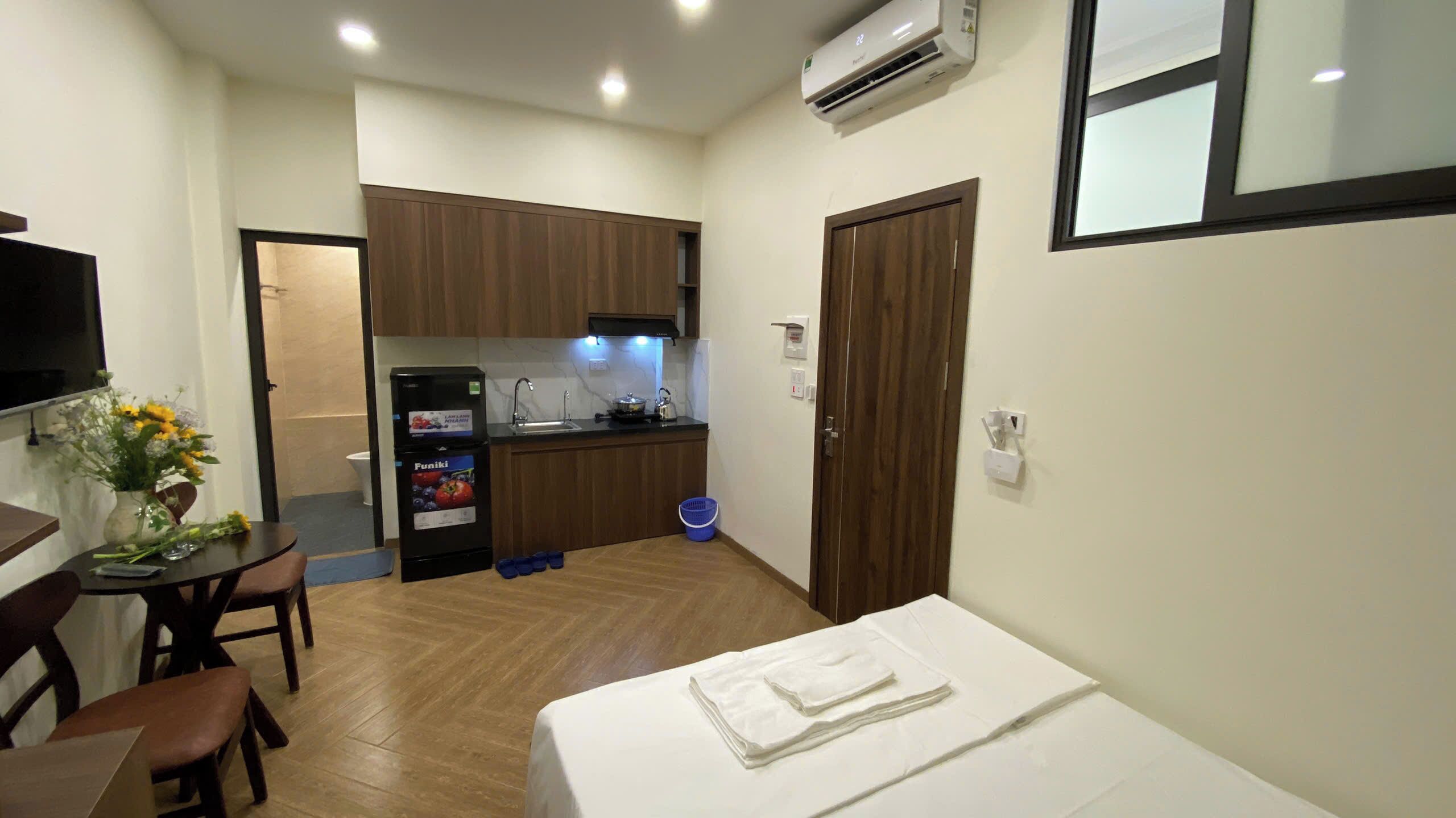A compact hotel room with a bed, a small dining table, and a kitchenette.