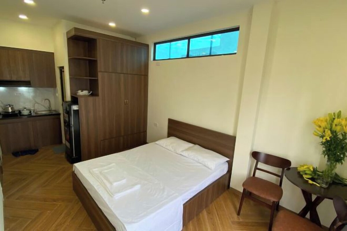 Una habitación compacta con cama, una pequeña mesa con sillas, kitchenette y ventana.