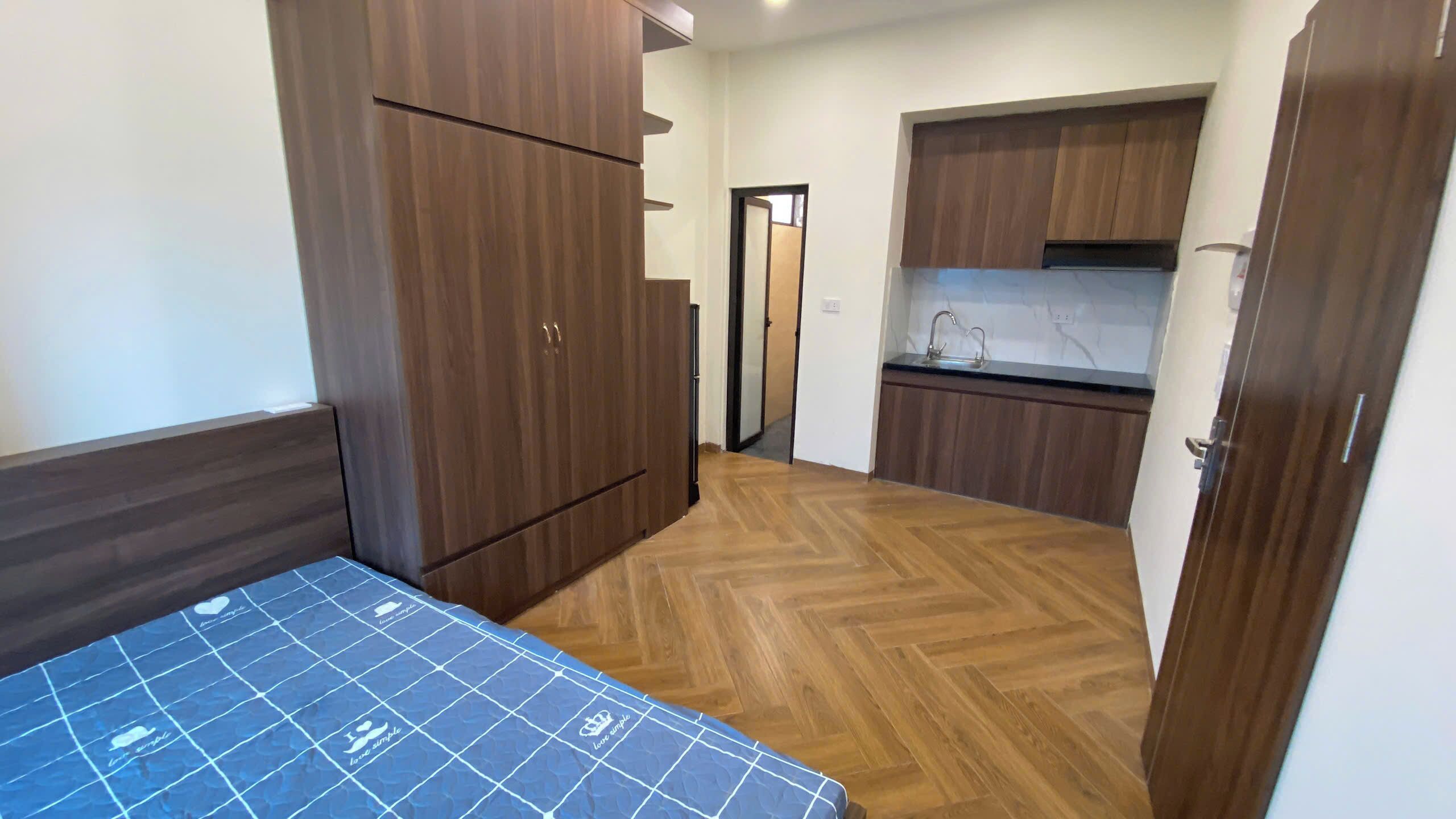 Una habitación pequeña con cama, armario y kitchenette.