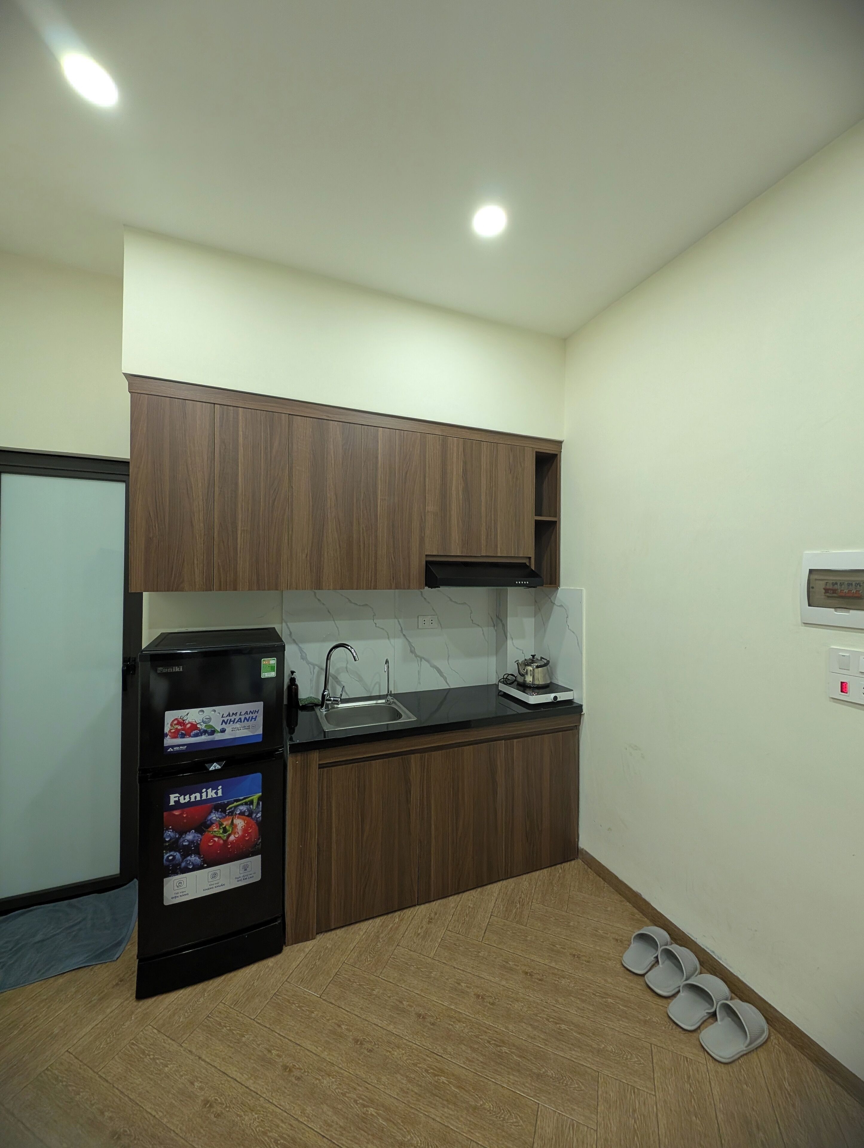 A compact kitchen with wooden cabinets, a black refrigerator, a sink, and a small countertop.
